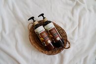 Overhead view of natural argan oil shampoo and conditioner in a wicker basket.