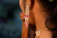 An intricate earring and necklace adorn a woman's ear, showcasing craftsmanship and style.