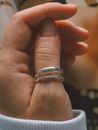 Detailed shot of a hand with silver rings, natural lighting.