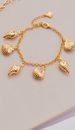 Close-up of a gold seashell bracelet showcasing its elegant design on a neutral background.