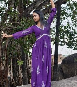 Woman in purple dress posing gracefully under a banyan tree in Tamil Nadu.