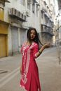 A woman in traditional attire poses in a vibrant street of Mumbai, India.