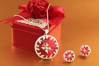 Silver jewelry set with red accents beside a decorative gift box.